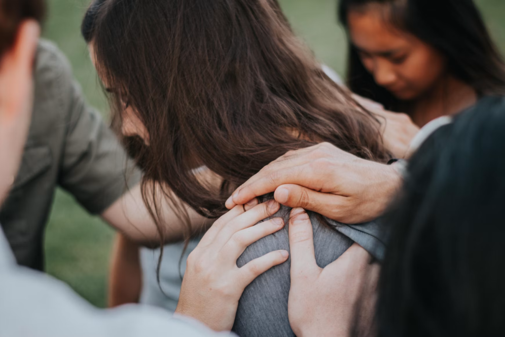 Mans posades sobre l'espatlla d'una persona en oració, discipulat i crida espiritual